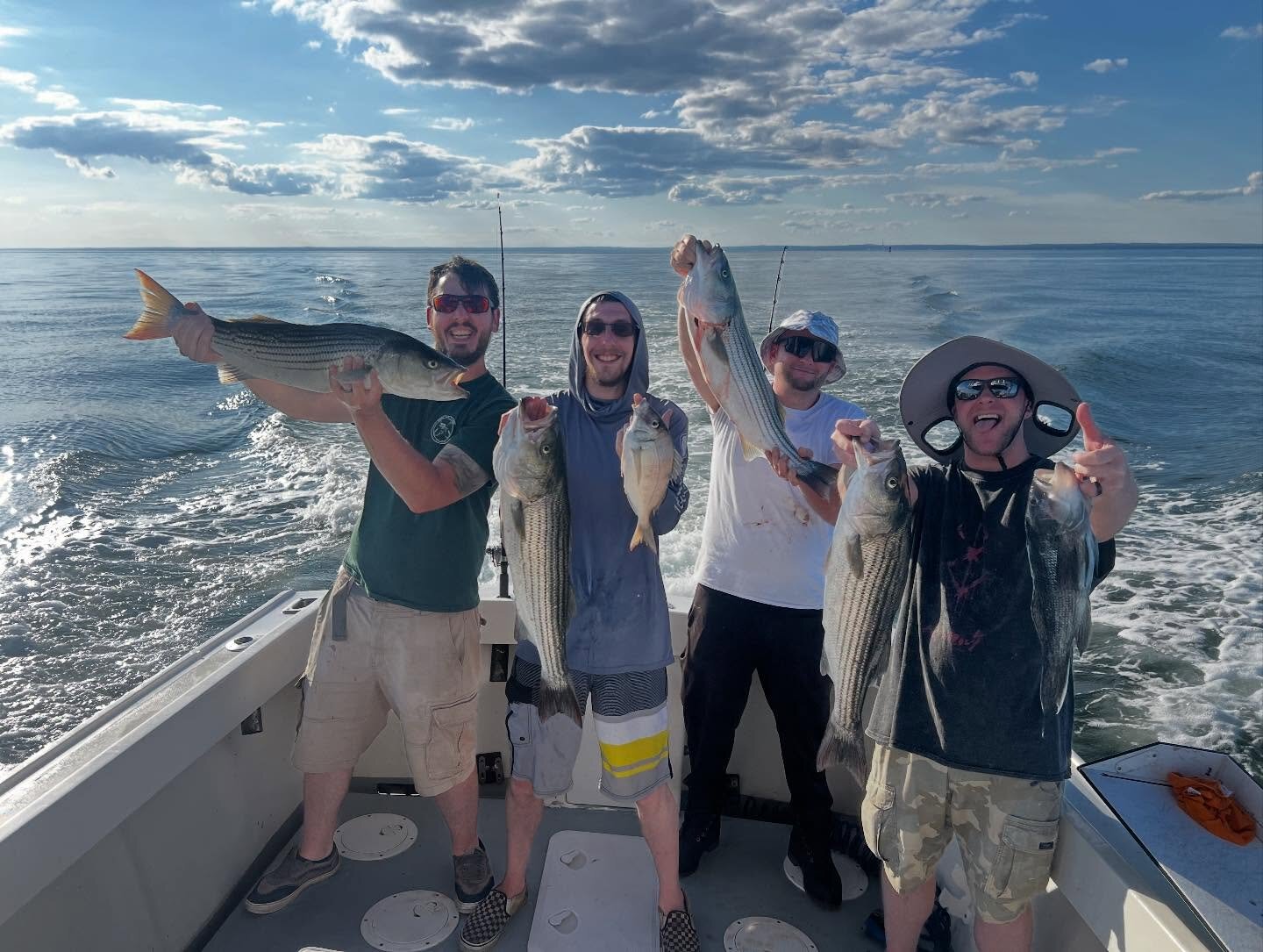 Four buddies holding striped bass at sunset