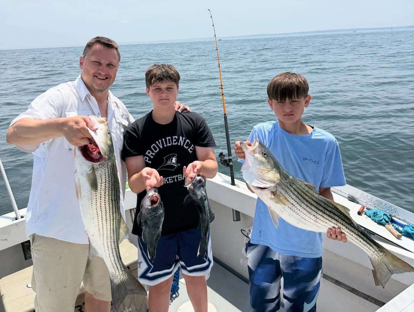 Dad and two sons with striped bass and sea bass