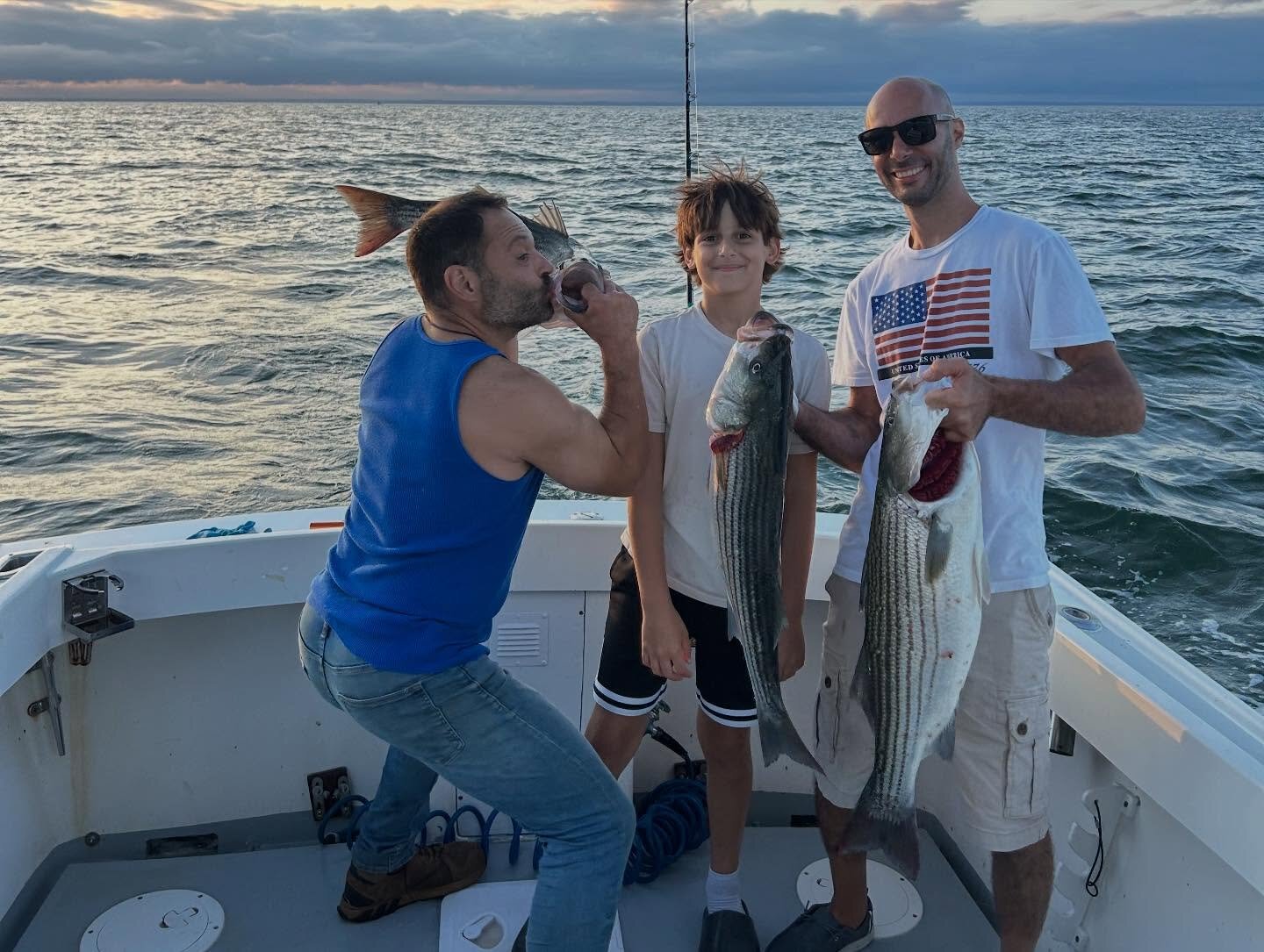 Family trip with kid holding his first striped bass