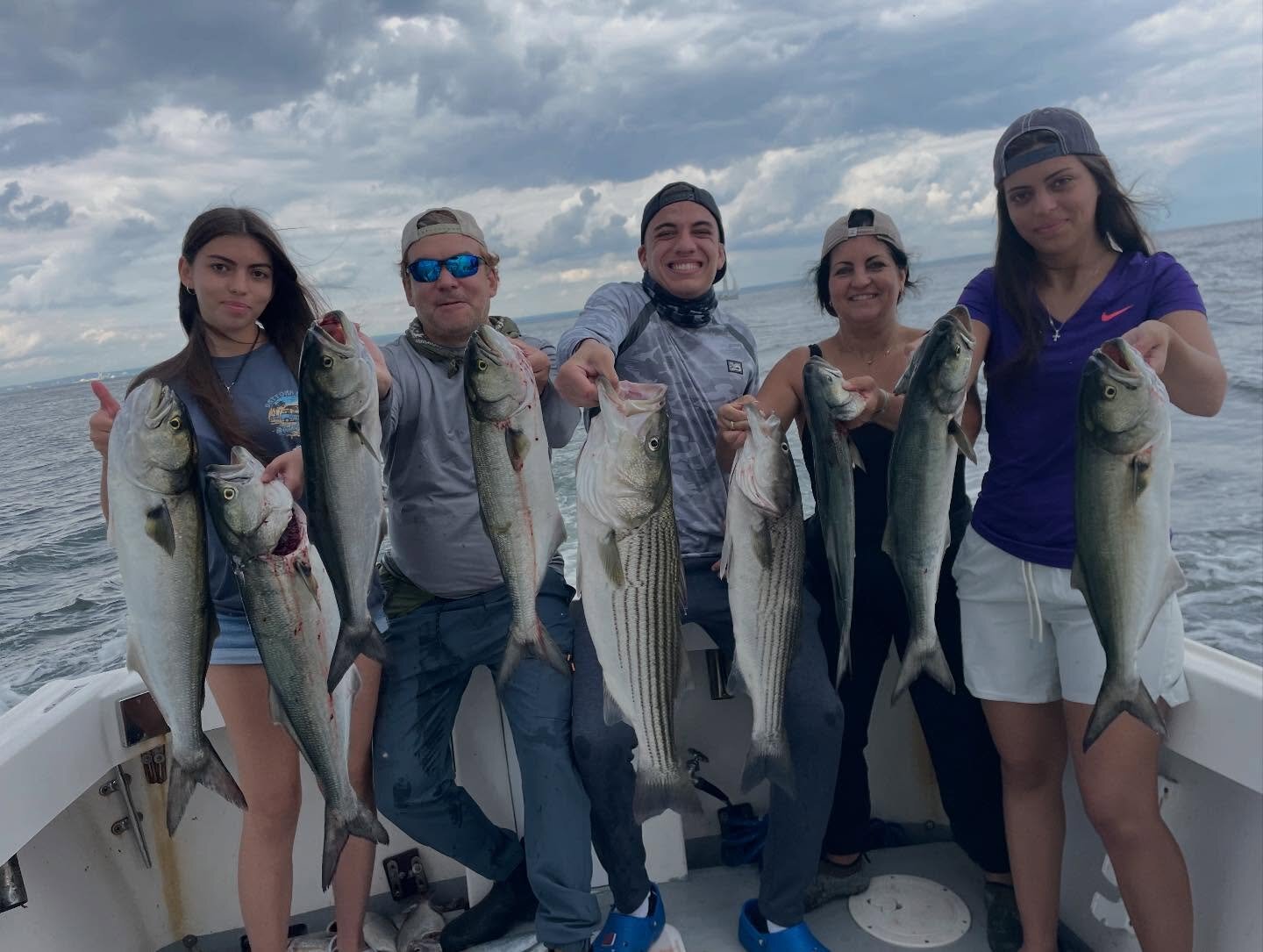 Family of five anglers holding stripers and bluefish