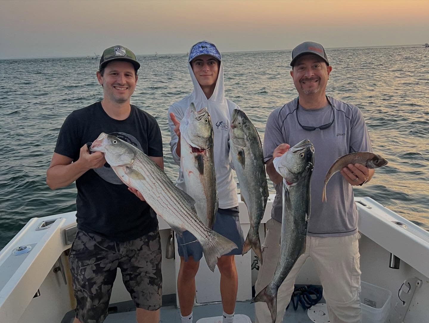 Three anglers with striped bass and bluefish